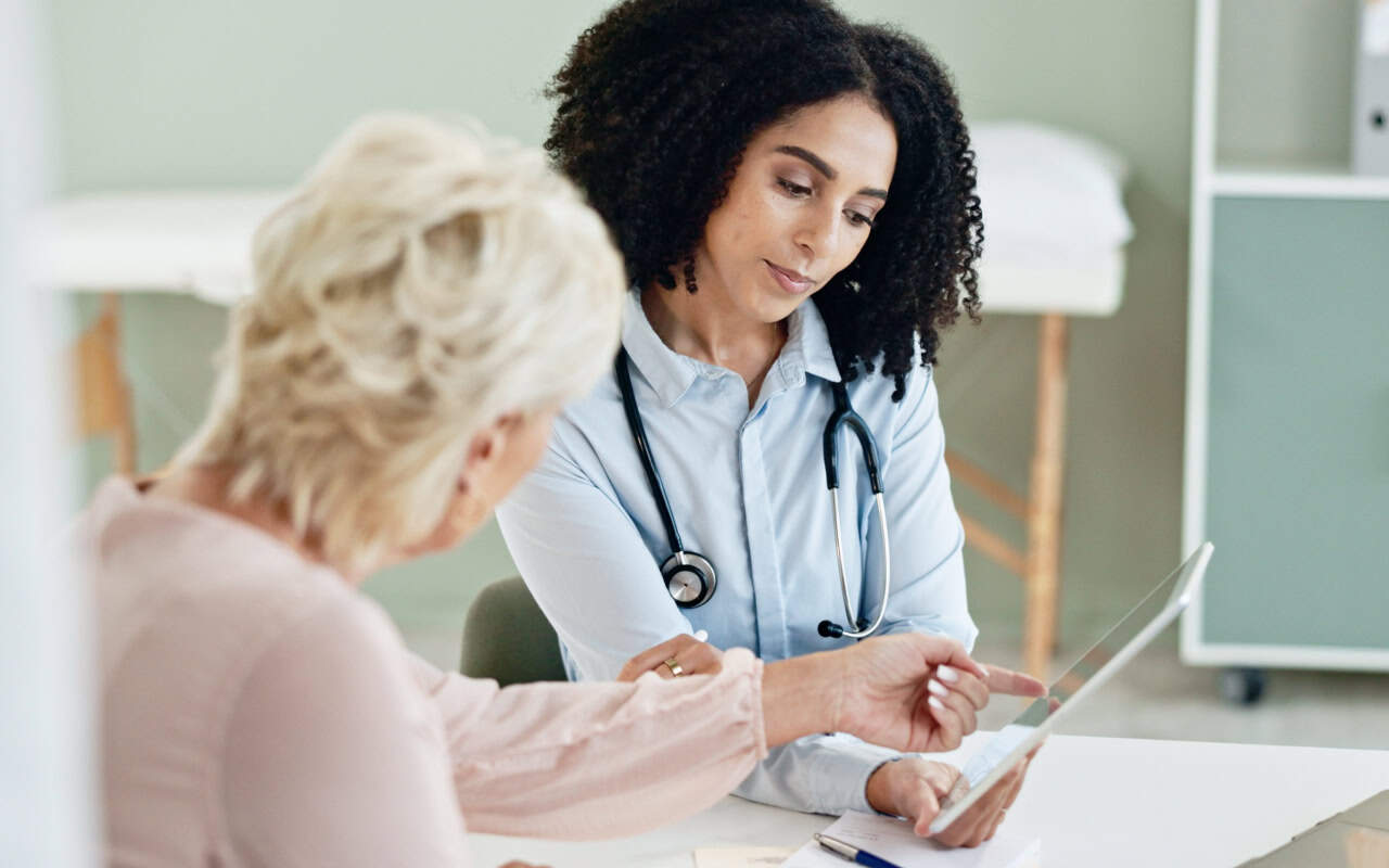A doctor showcasing her treatment notes with a patient on her notebook