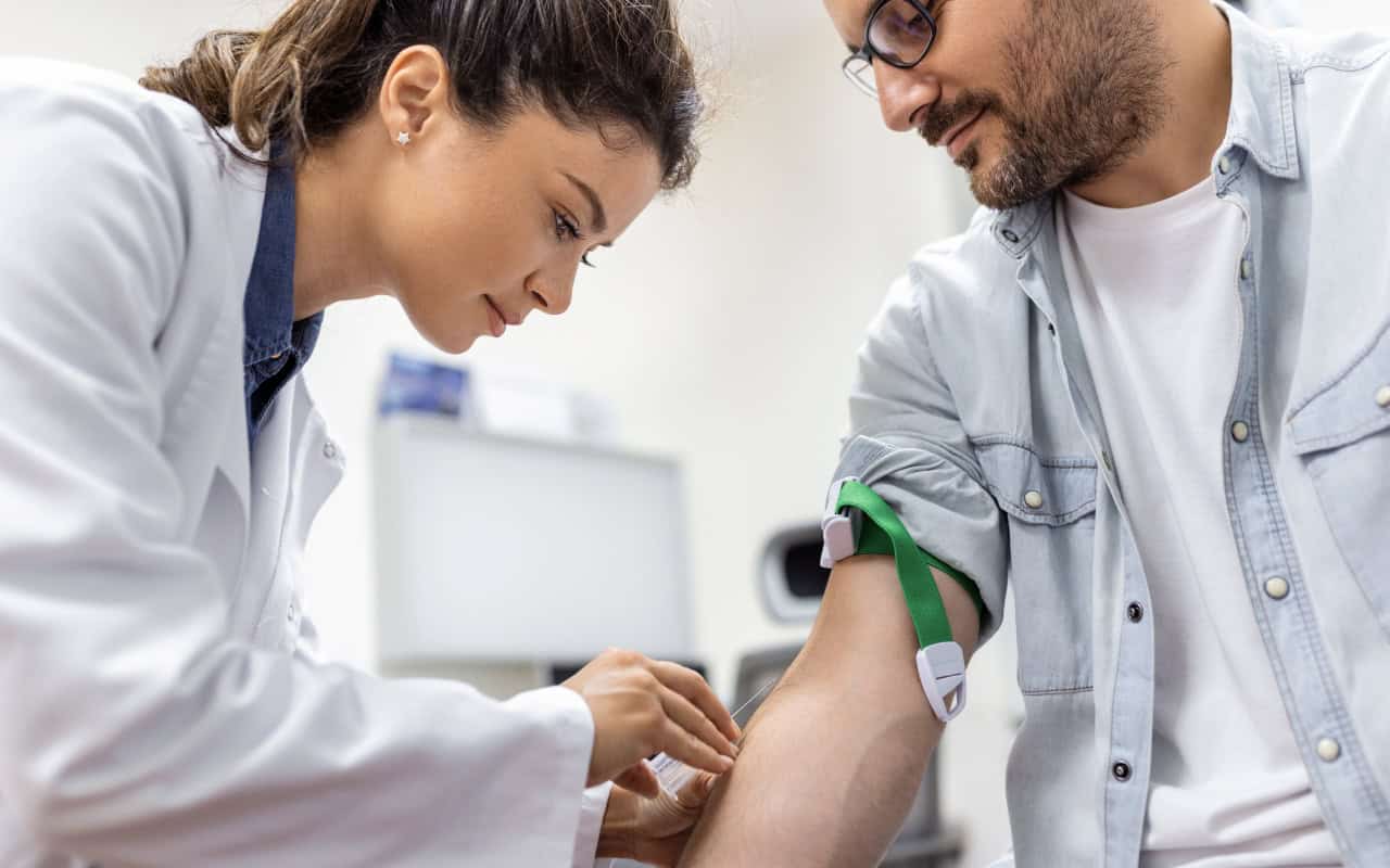 Doctor tenderly providing an injection to a man via the arm